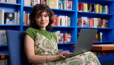 Tatiana, a real person with narcolepsy with cataplexy taking WAKIX, sitting with their laptop
