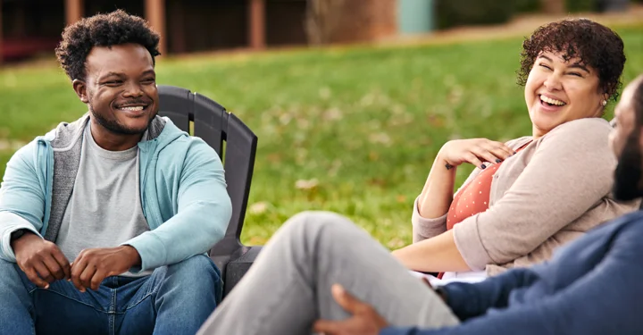Chris, a real person with narcolepsy with cataplexy taking WAKIX, sitting with friends outdoors
