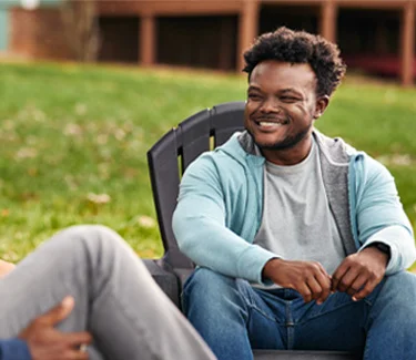 Chris, a real person with narcolepsy with cataplexy taking WAKIX, sitting with friends outdoors